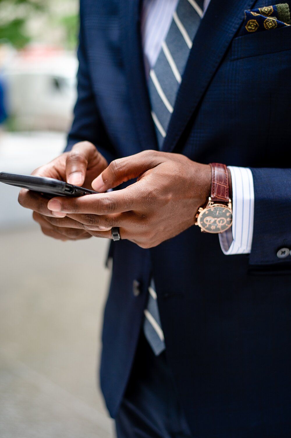 Homem negro com terno azul mexendo no celular